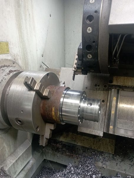 Machine-outil en cours d'usinage d'une pièce métallique, copeaux visibles autour.