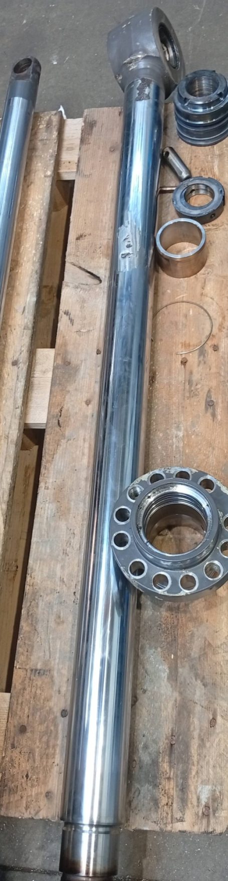 Tige métallique brillante avec des accessoires en métal posée sur un plateau en bois.