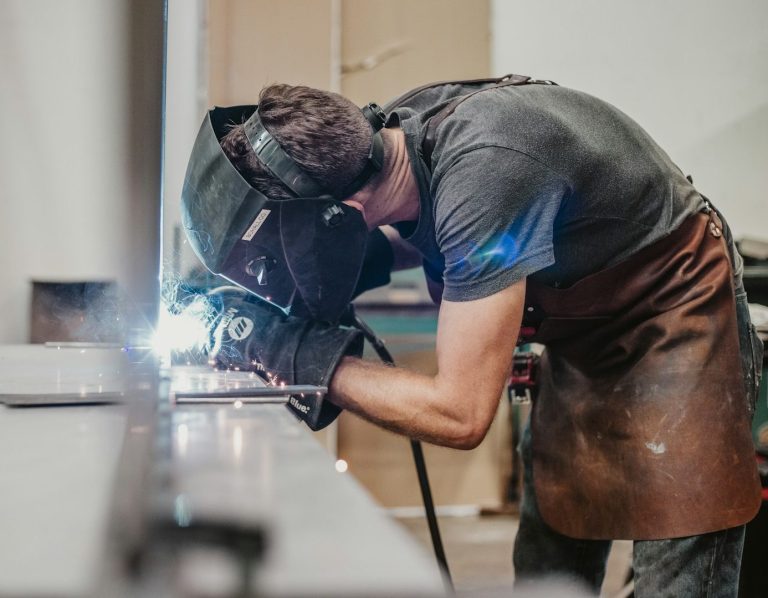 Un soudeur en train de travailler, créant des étincelles avec un équipement de protection.